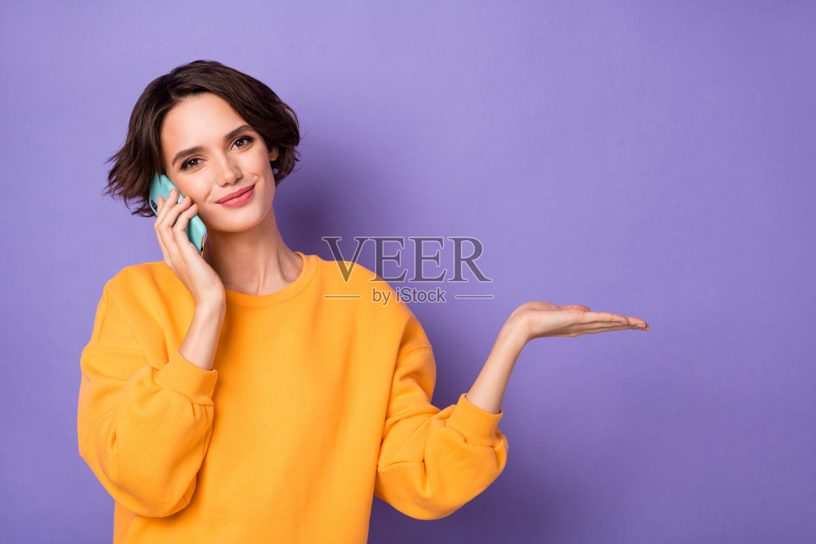 吸引人的女士在紫色背景上打电话，手臂伸出，展示空白空间的提议。照片摄影图片