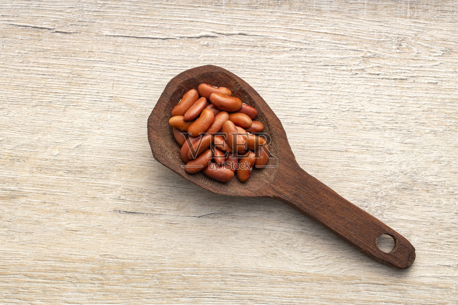 干豆在勺子上，是餐桌上的主食 - 普通菜豆。照片摄影图片