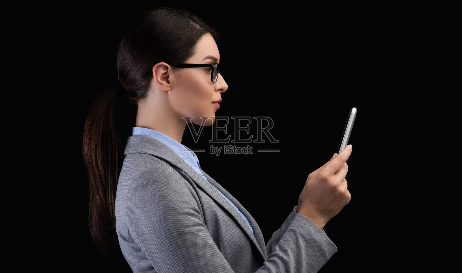 商界女性在黑色背景下使用智能手机面部识别系统照片摄影图片