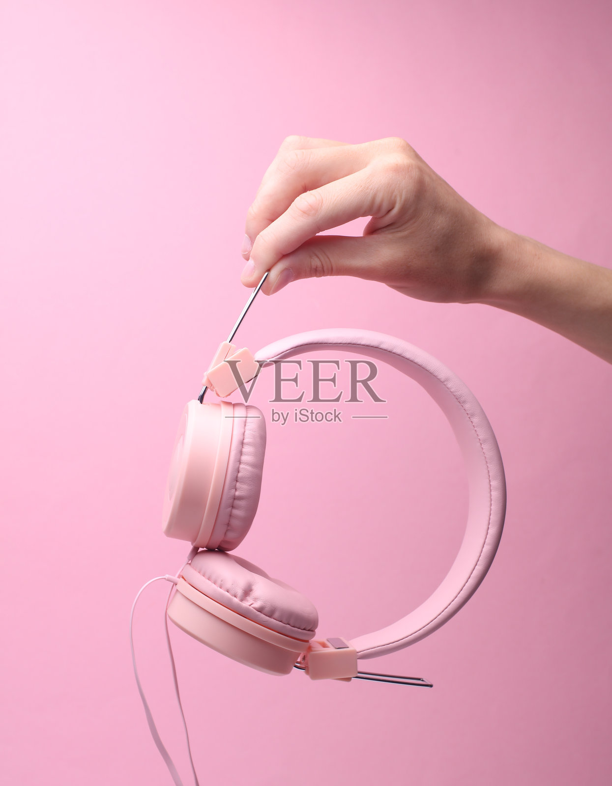 粉色背景上女性手中的立体耳机照片摄影图片