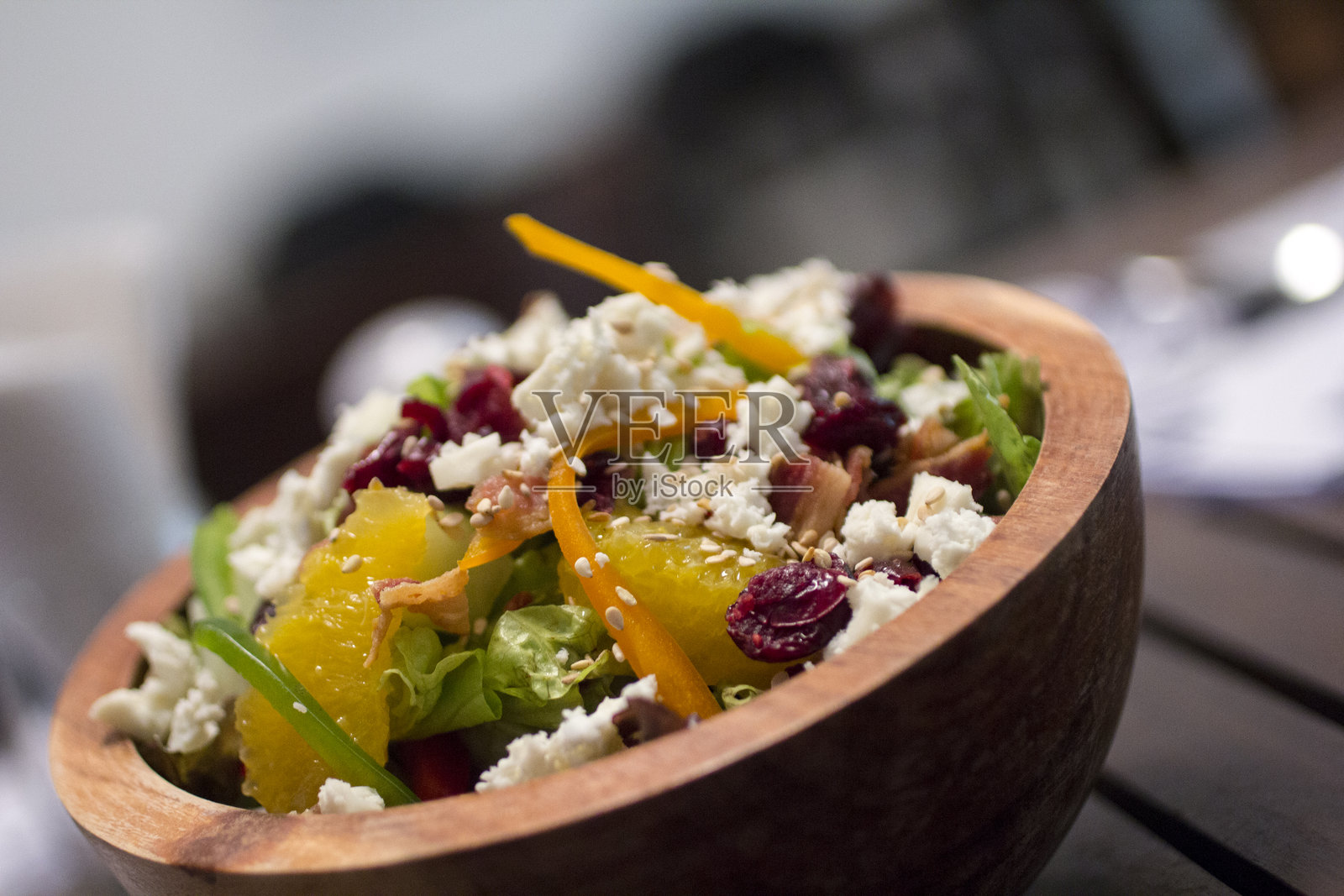 健身沙拉，配有瑞可达奶酪和干蔓越莓，放在一个乡村风格的木碗中，侧面特写。照片摄影图片