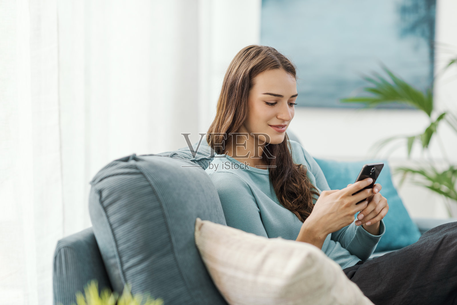 美丽的年轻女性在家放松并使用智能手机照片摄影图片