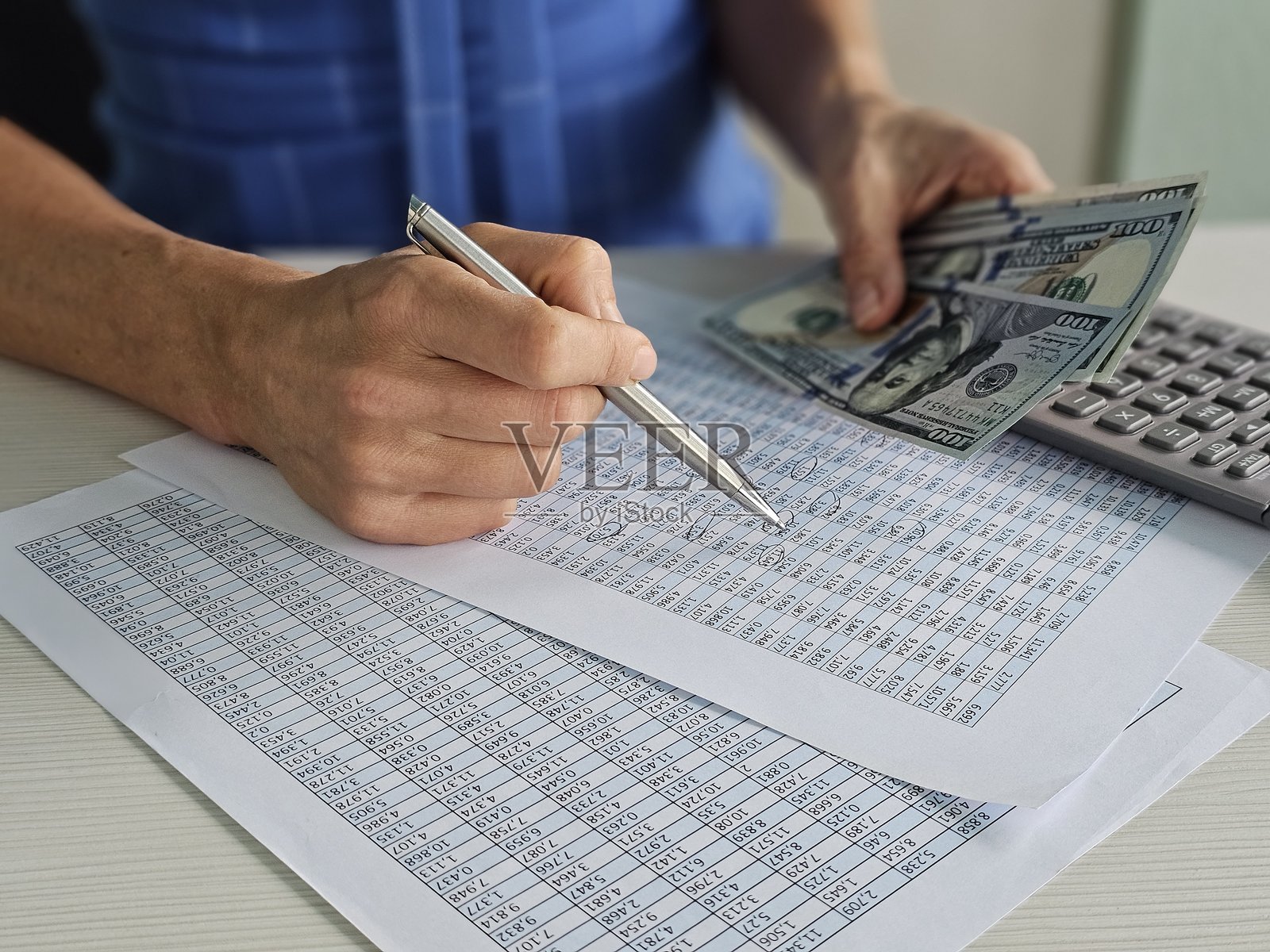 个人在分析财务数据，同时手握现金并进行计算准备照片摄影图片