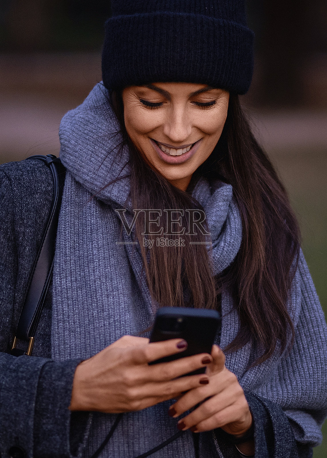 棕发女性在秋天的公园里走路并使用智能手机照片摄影图片