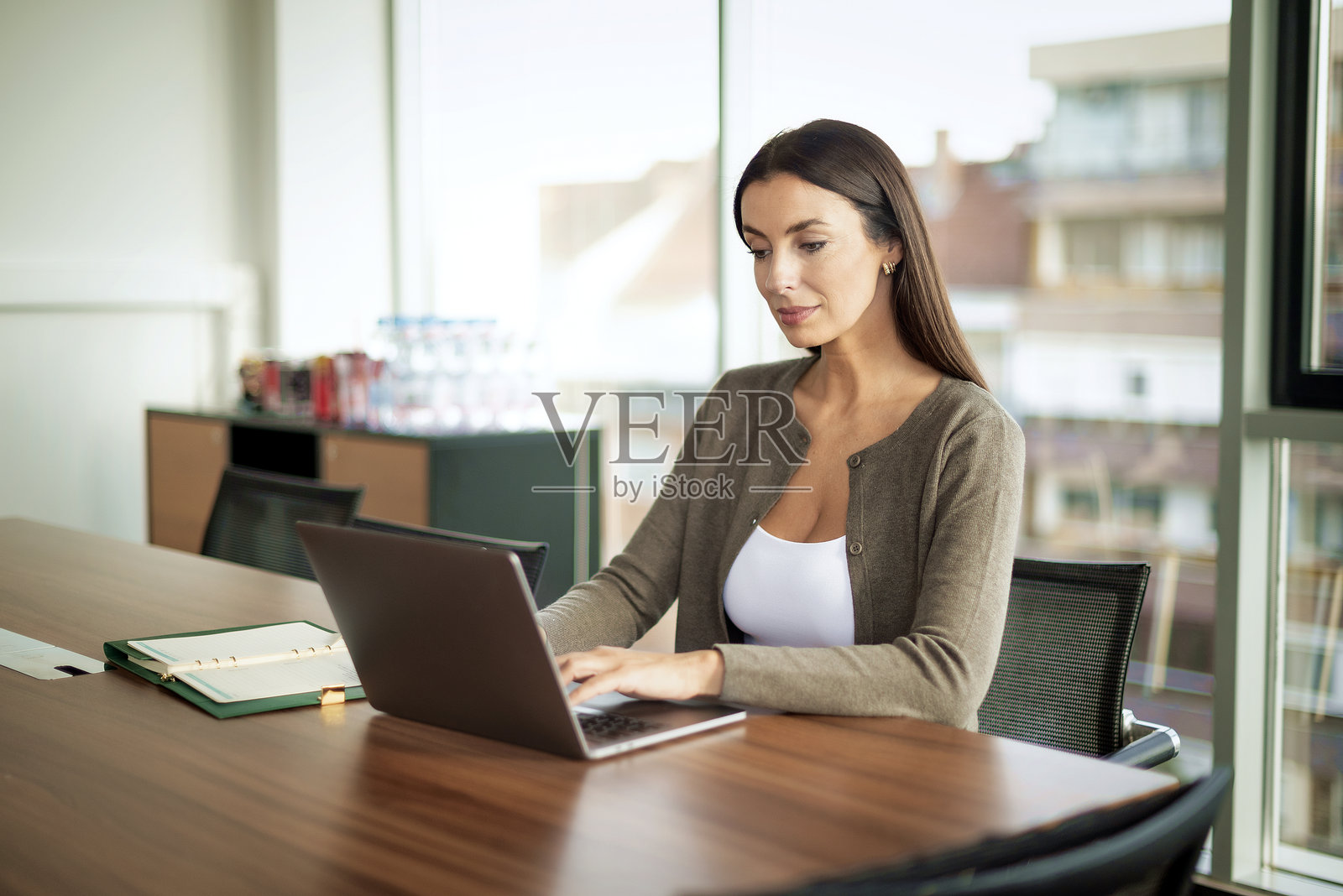 迷人的女商人在办公桌前使用笔记本电脑照片摄影图片