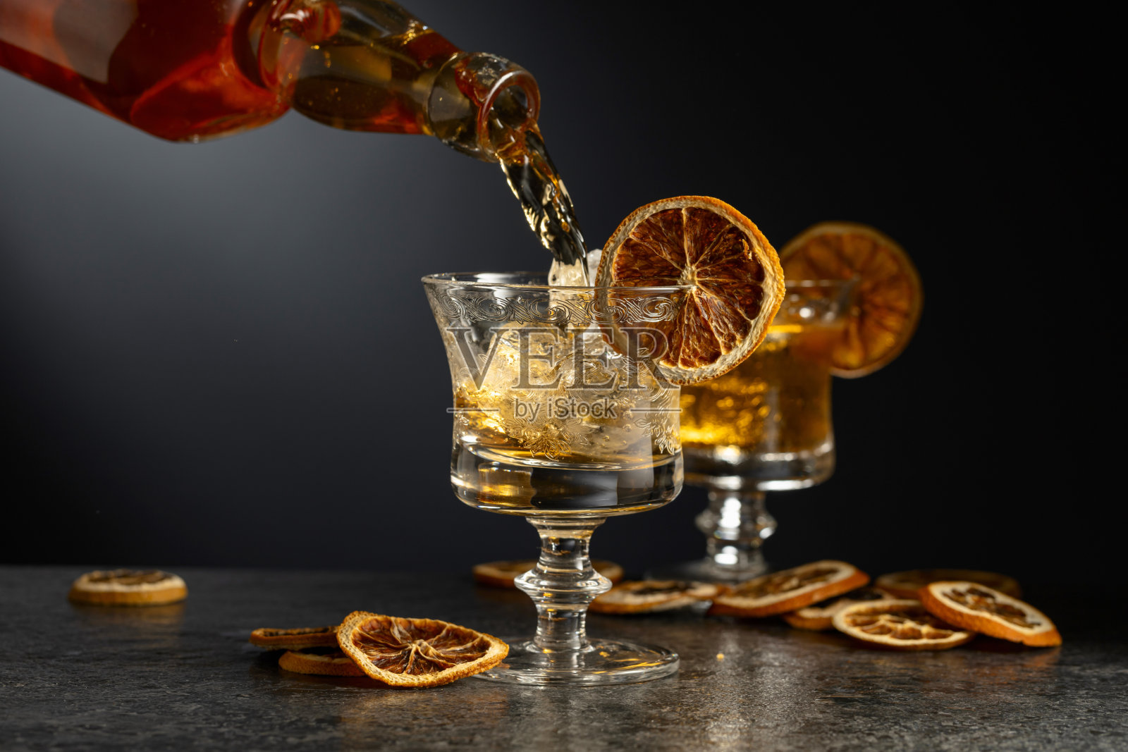 朗姆酒从瓶子倒入装有冰块的玻璃杯中。照片摄影图片