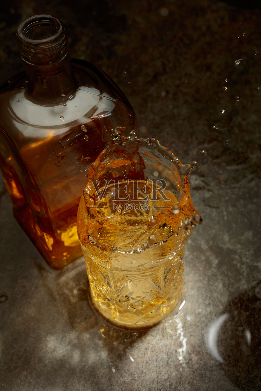 冰块掉入装有威士忌的水晶杯中。照片摄影图片