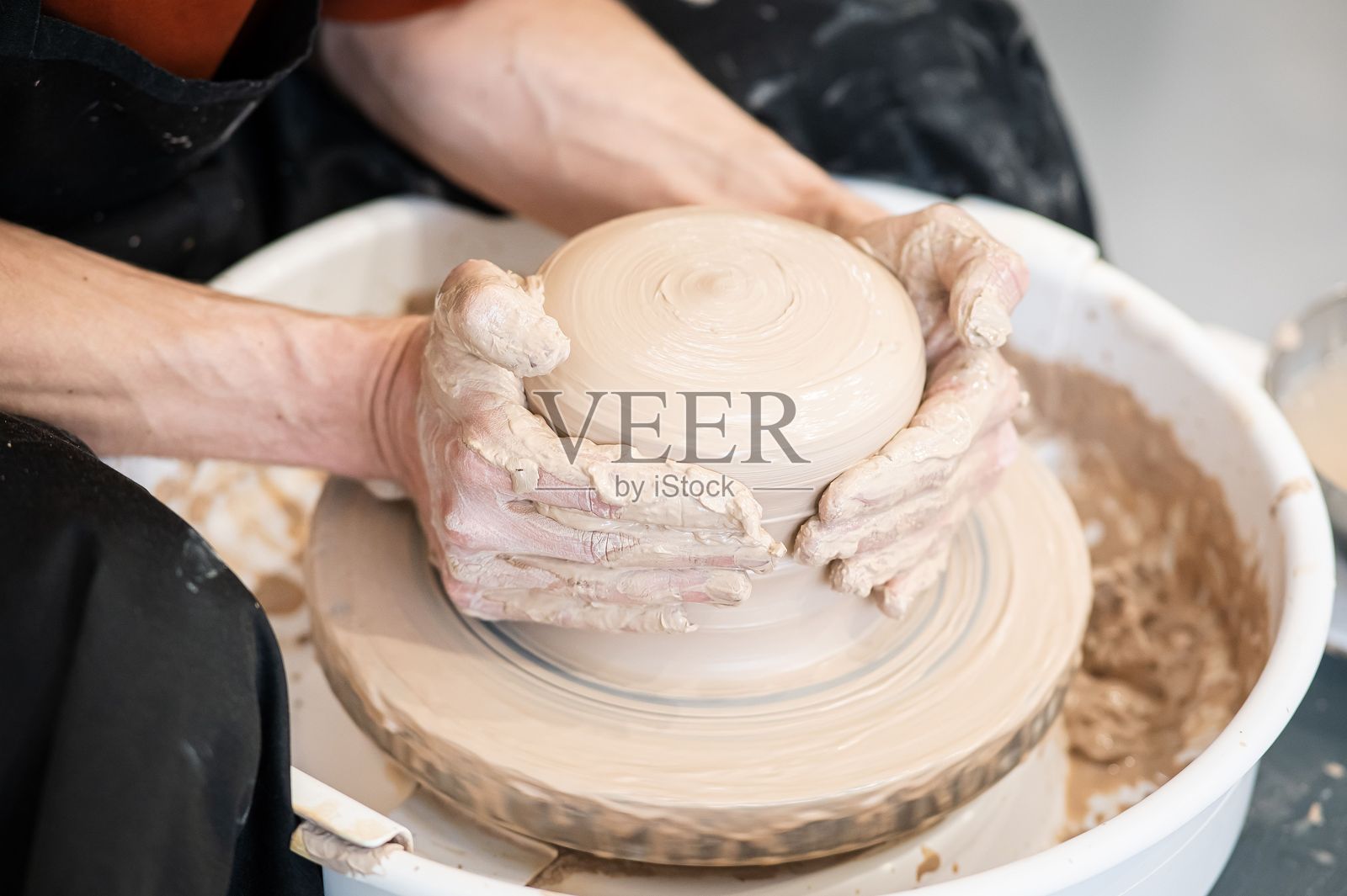 陶艺师的双手在陶轮上进行细致的工作。照片摄影图片
