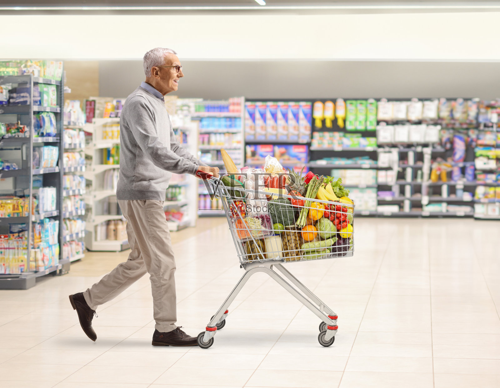 成熟男性顾客推着购物车走路照片摄影图片