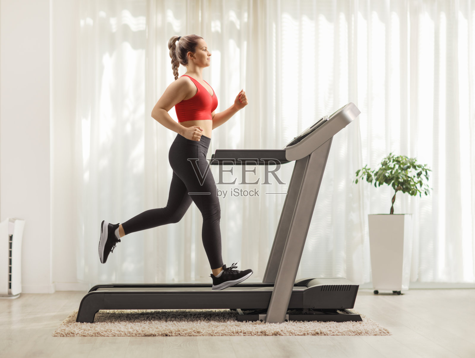 强壮的年轻女性在家中跑步机上跑步照片摄影图片