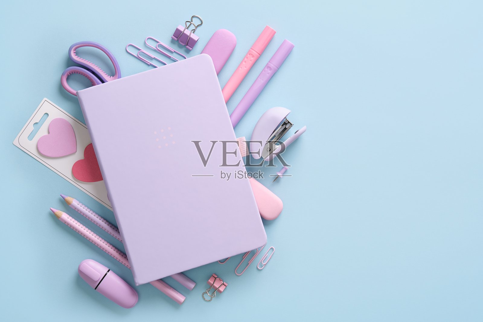 粉蓝背景上各种粉色和紫色的学校及办公文具的组合。可添加您的文字。照片摄影图片