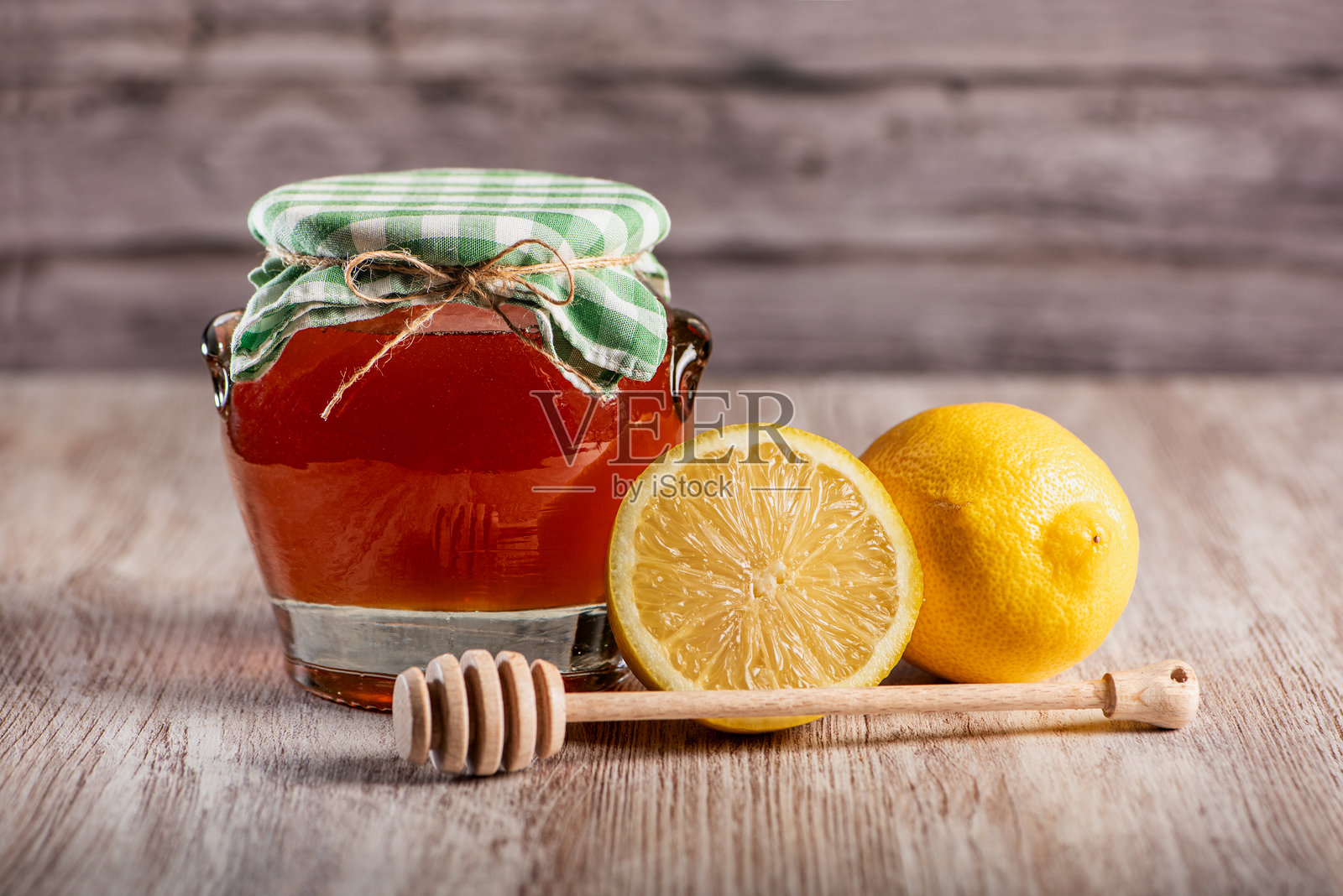 一罐用布覆盖的花蜜，旁边有一把蜂蜜勺和一些柠檬，有助于缓解流感和感冒症状等多种功效，特写镜头。照片摄影图片