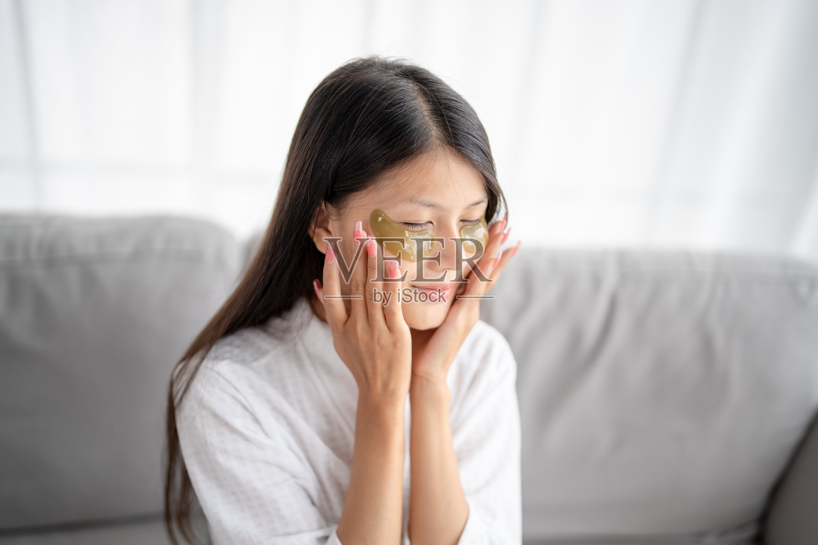 亚洲女性的日常美容护肤程序，使用硅胶眼贴自我护理和放松，面带微笑，愉快地使用护肤产品。照片摄影图片