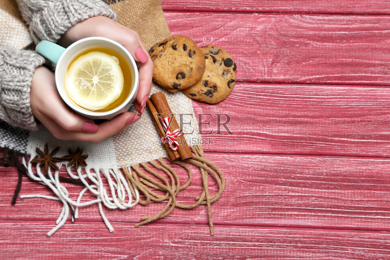 女人的手握着茶杯，放在木桌上照片摄影图片