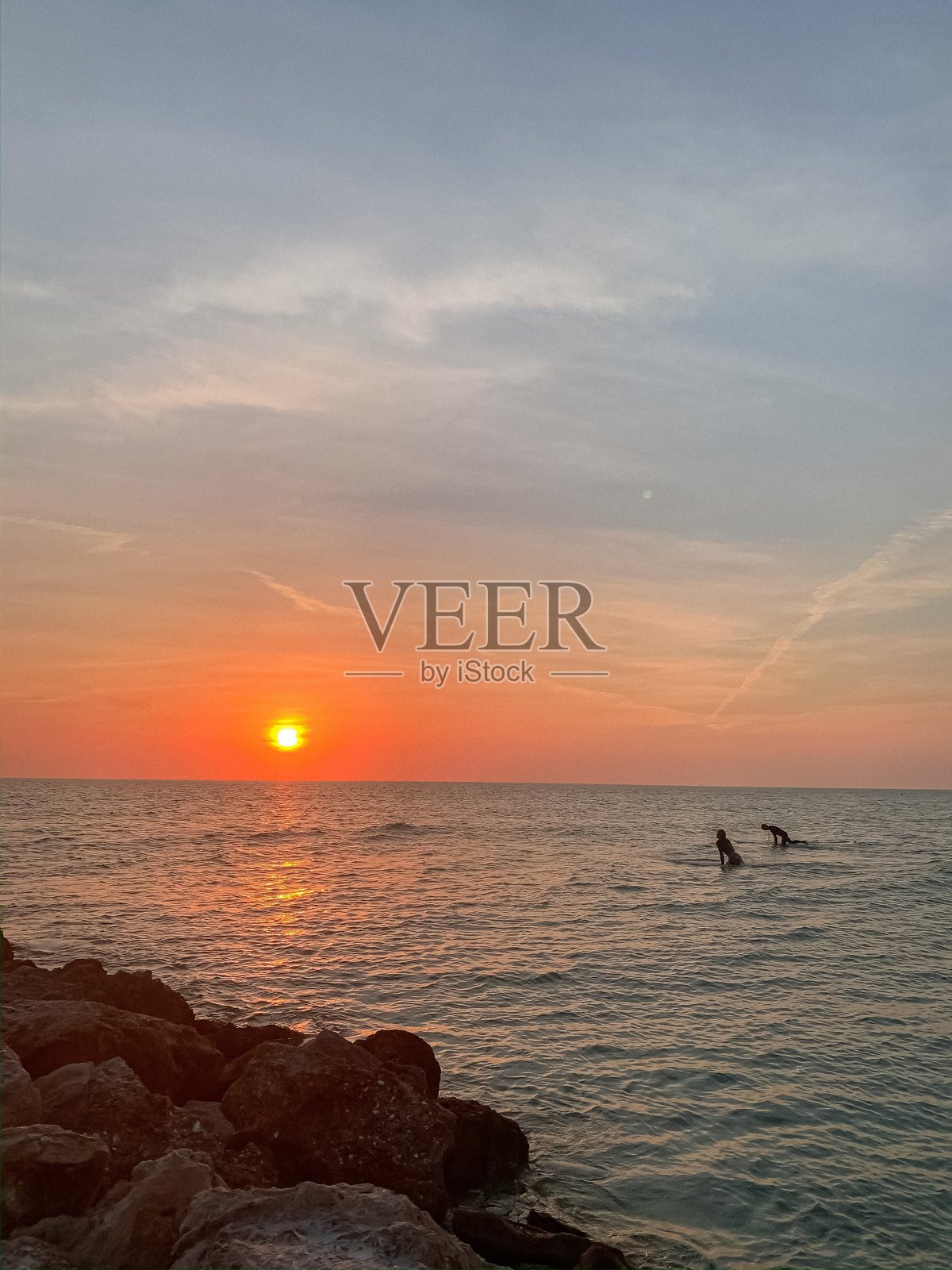 日落时分的冲浪者在海洋中照片摄影图片