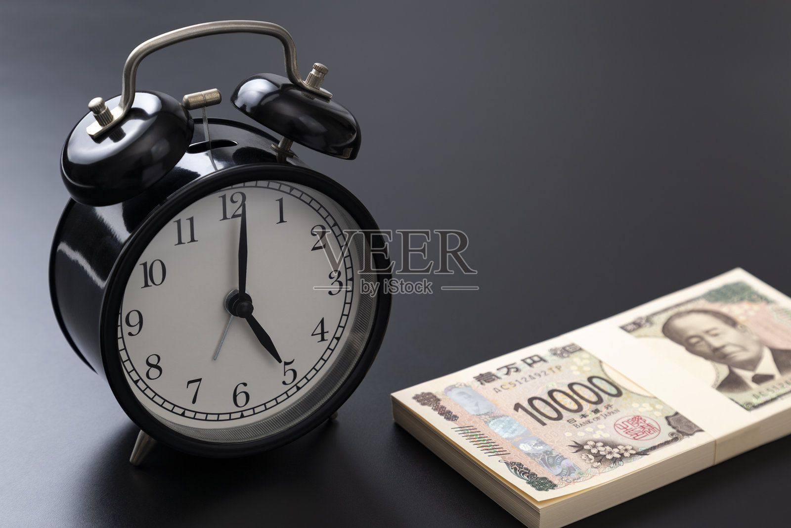 黑色背景上的时钟和一叠钞票。照片摄影图片