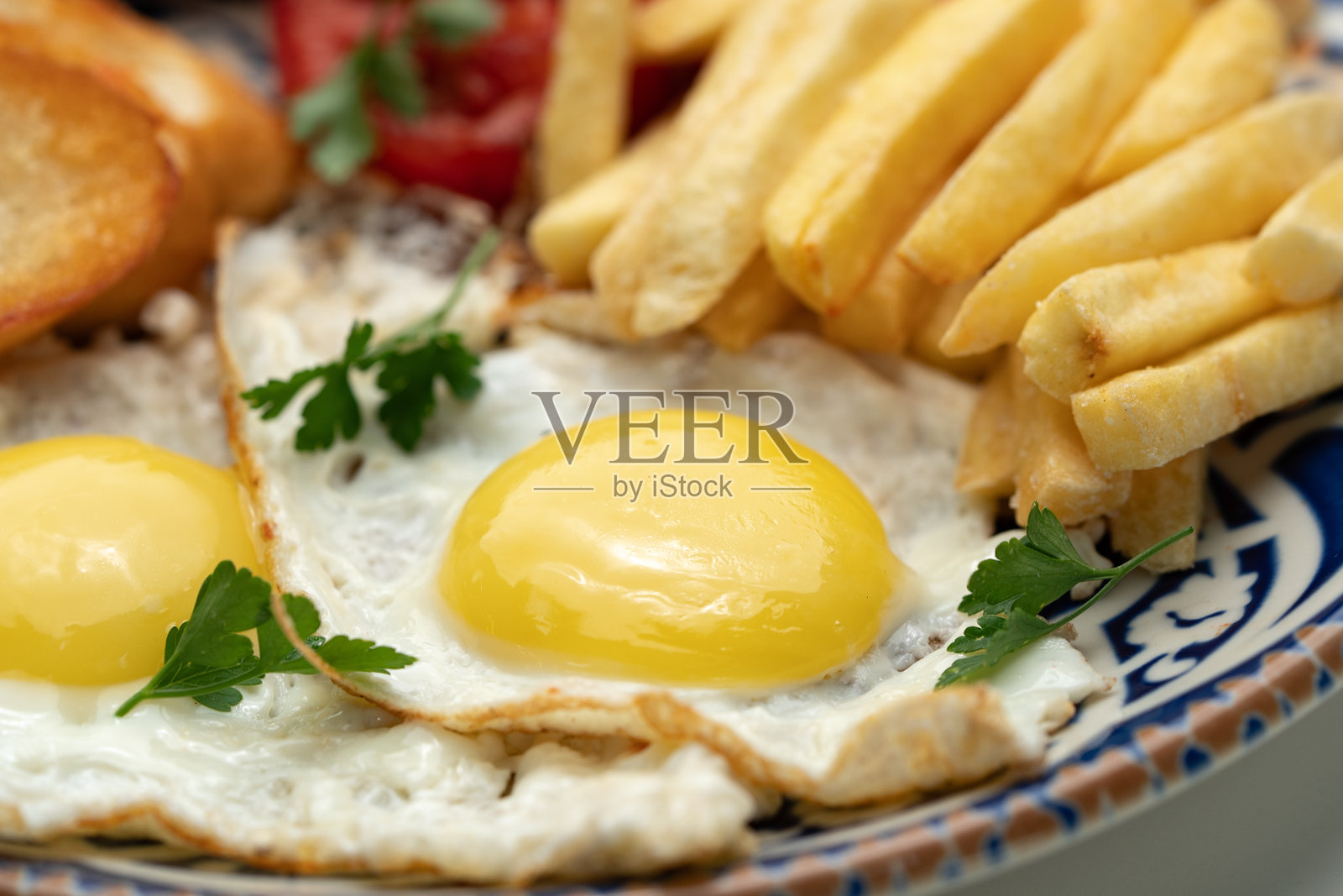 装饰蓝盘上的煎蛋、香肠、番茄和薯条早餐照片摄影图片