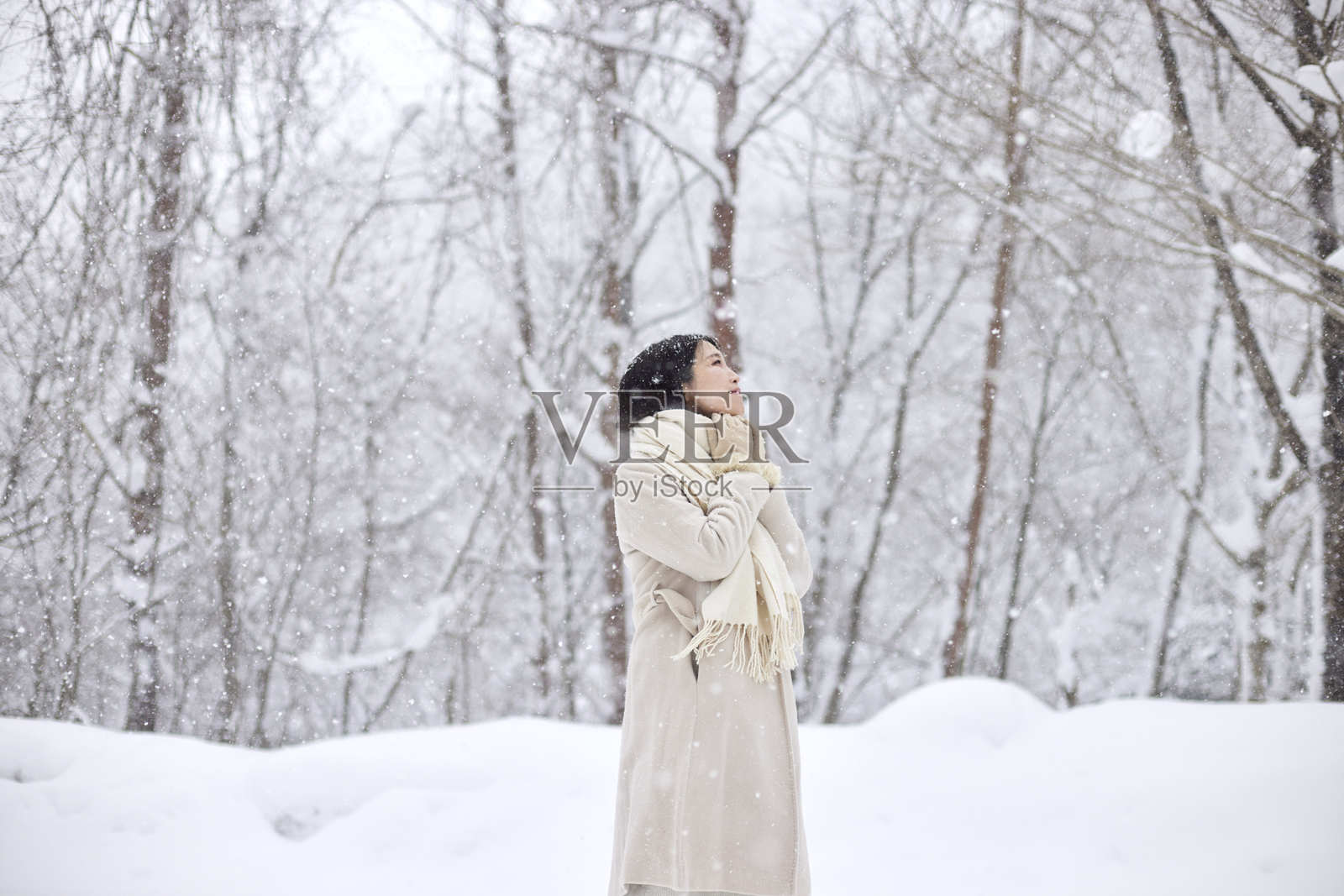 一位戴着围巾的日本女性站在雪白的冬季国家中照片摄影图片