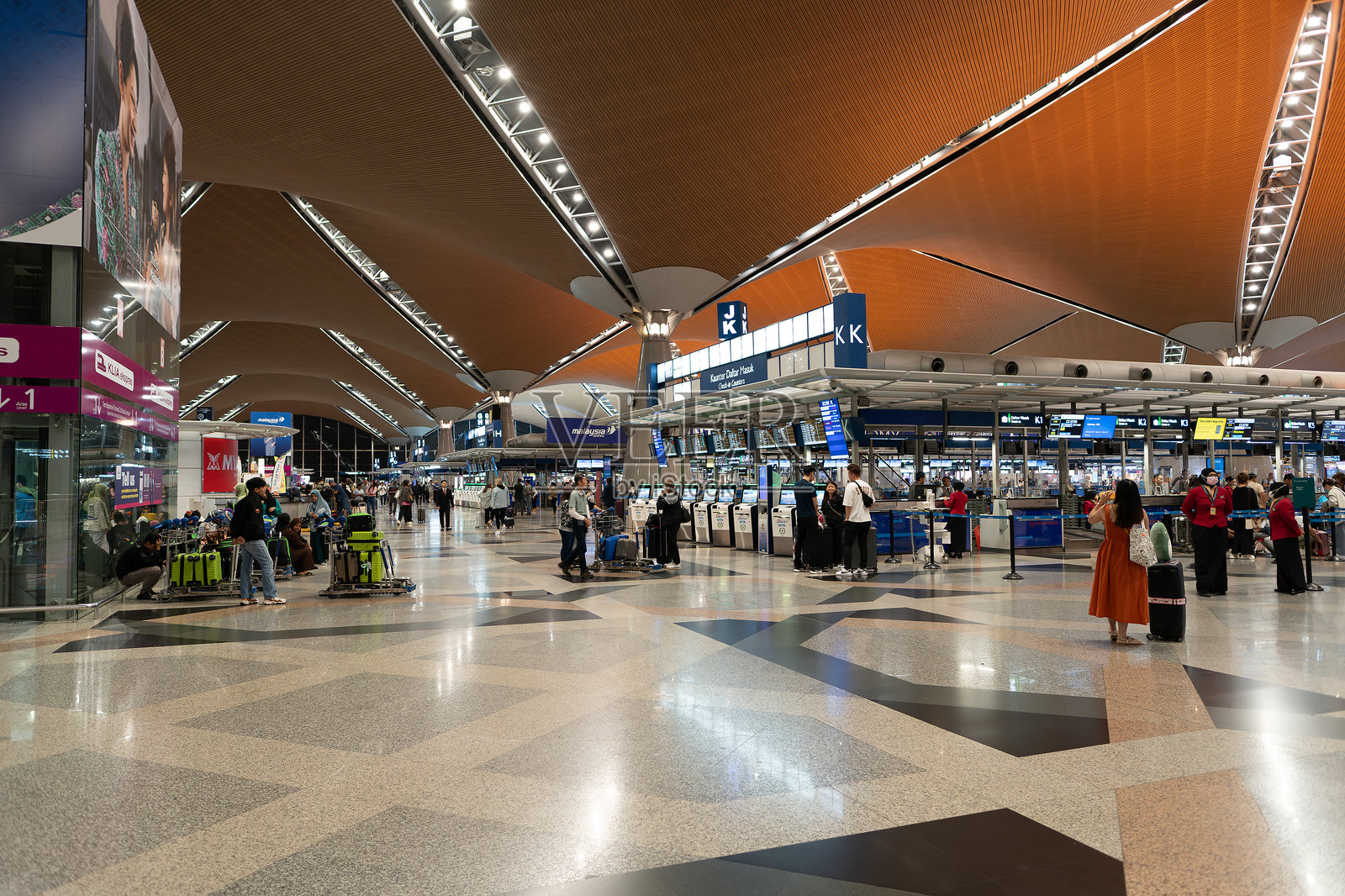 吉隆坡国际机场的值机区。值机过程包括乘客与航空公司工作人员互动，以核实文件、托运行李并领取登机牌。照片摄影图片