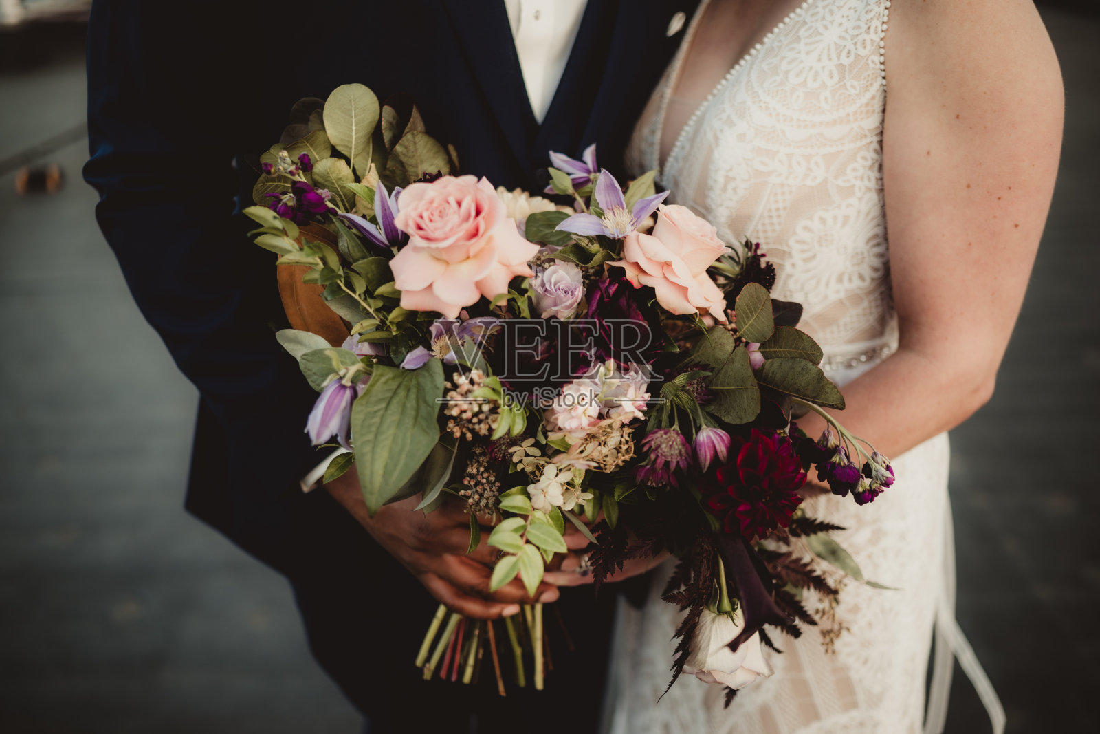 新娘和新郎站在一起，手捧波西米亚风格的花束照片摄影图片