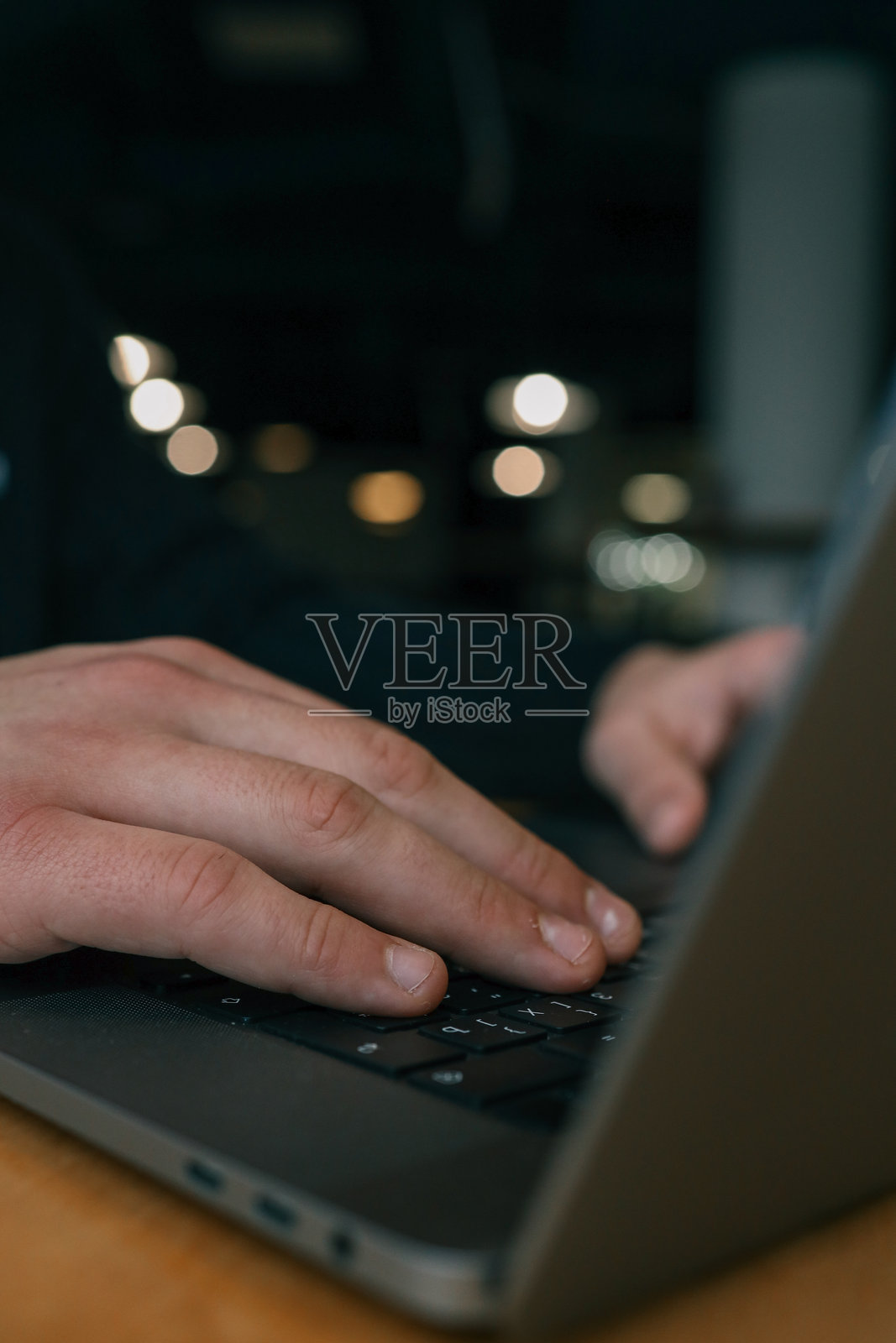 特写镜头下的手在笔记本电脑键盘上打字，模糊的散景背景营造出温馨而专注的工作氛围照片摄影图片