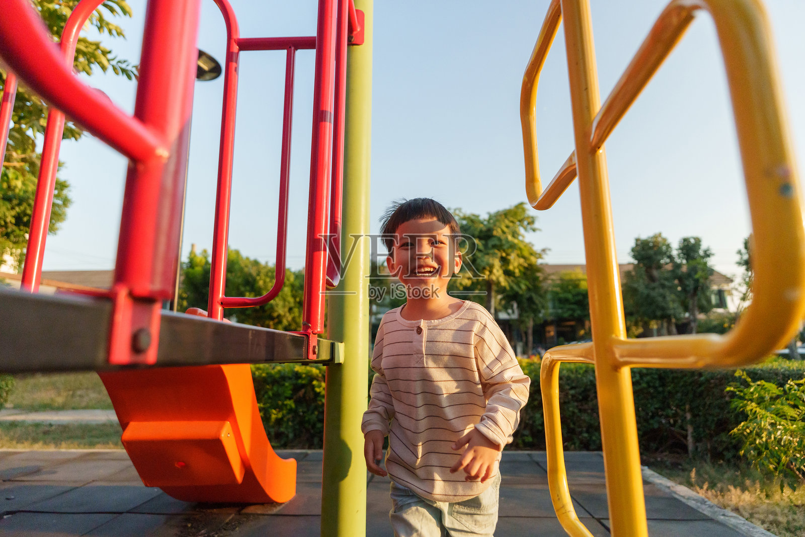 微笑的亚洲儿童在阳光明媚的下午享受五彩缤纷的游乐场玩耍时光照片摄影图片