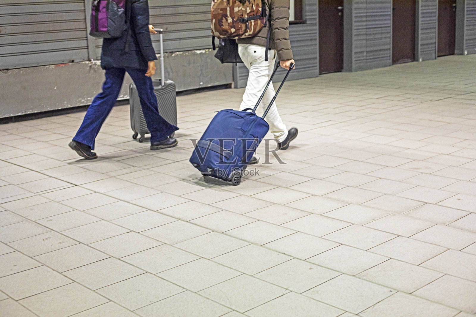 游客们在地下通道中拖着他们的行李箱。照片摄影图片