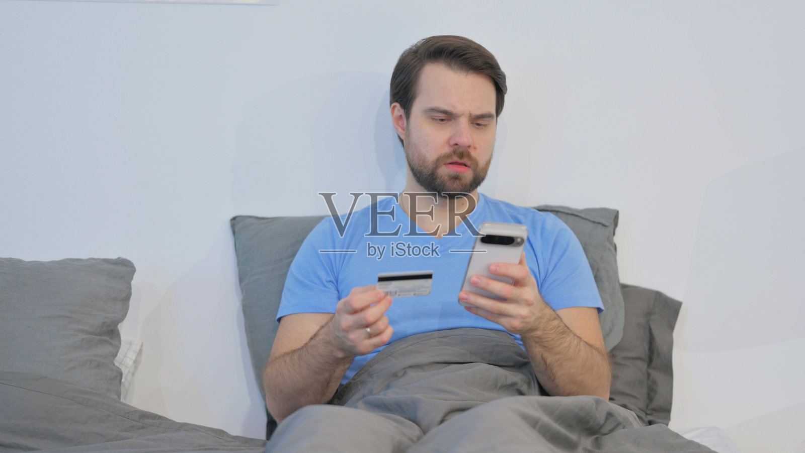 中年男子在床上因网购而感到沮丧照片摄影图片