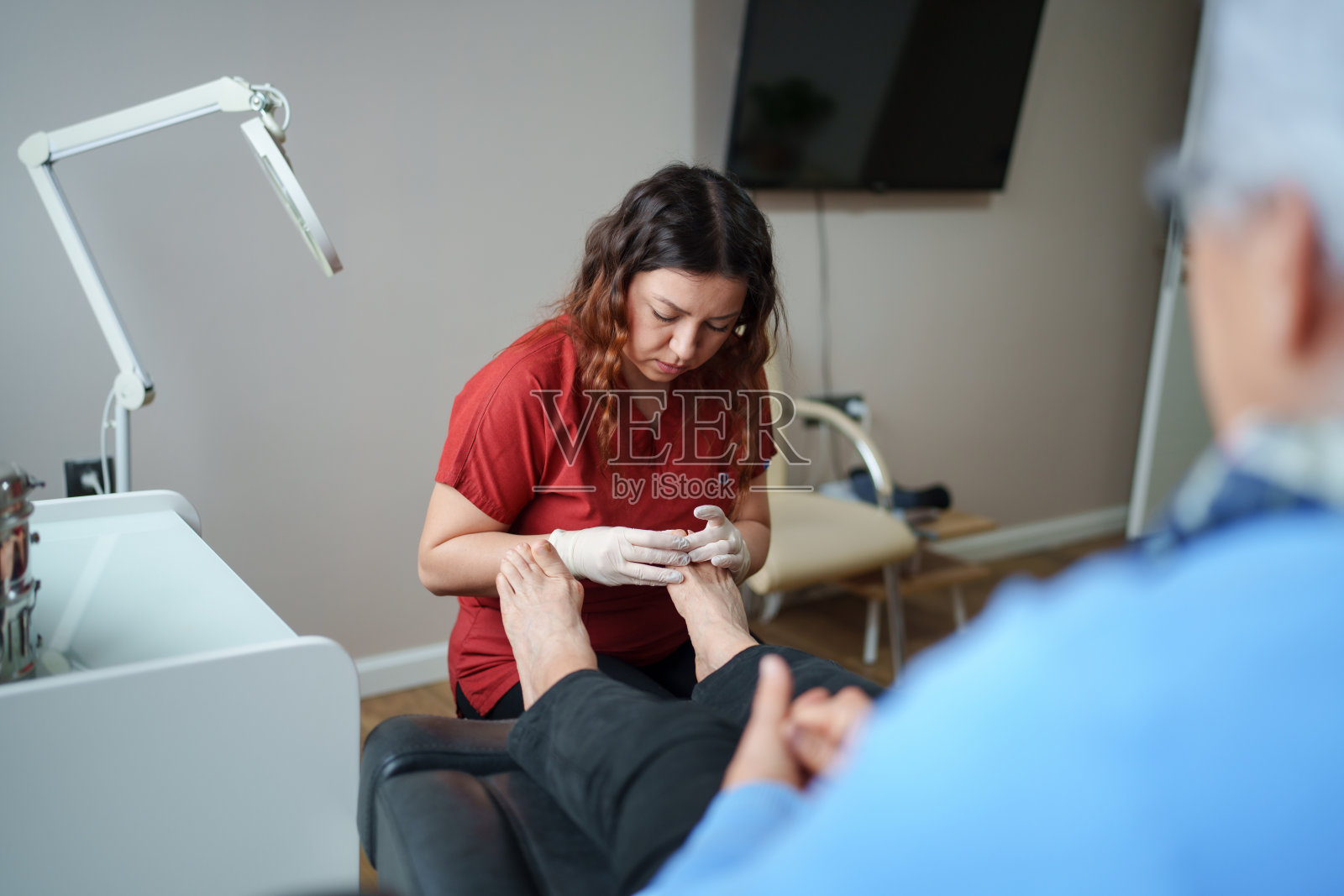 足病医生与患者在医疗检查室。照片摄影图片