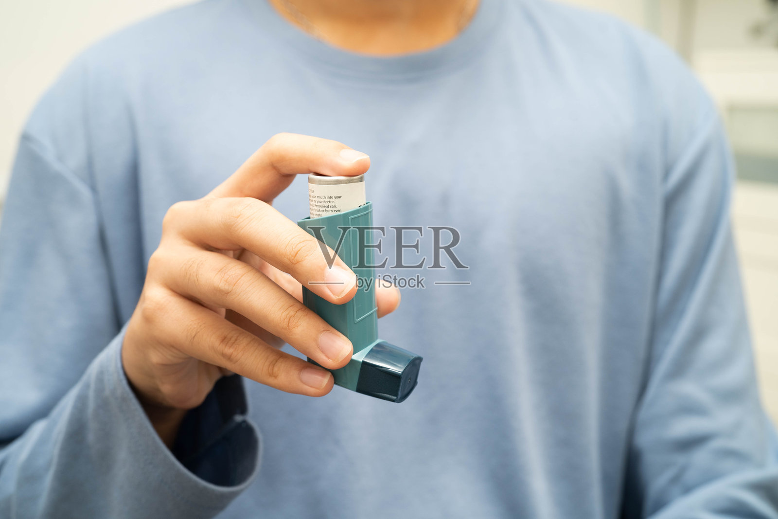 哮喘和慢性阻塞性肺病（COPD），亚洲年轻男子使用定量吸入器（MDI）。照片摄影图片