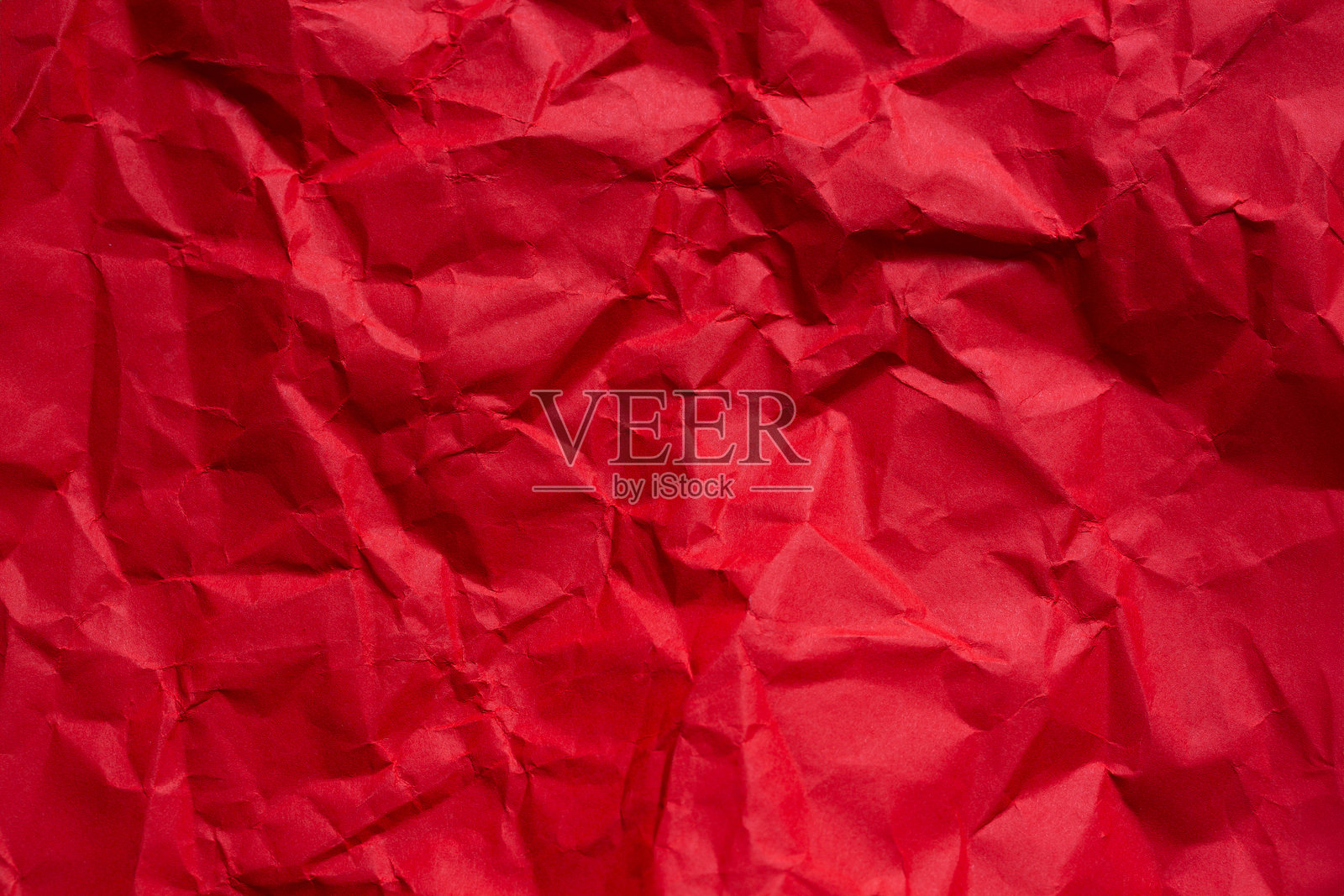 红色皱纹纸背景特写，特写深红色皱纹纸的纹理，深邃的阴影和高光形成抽象的艺术背景。照片摄影图片