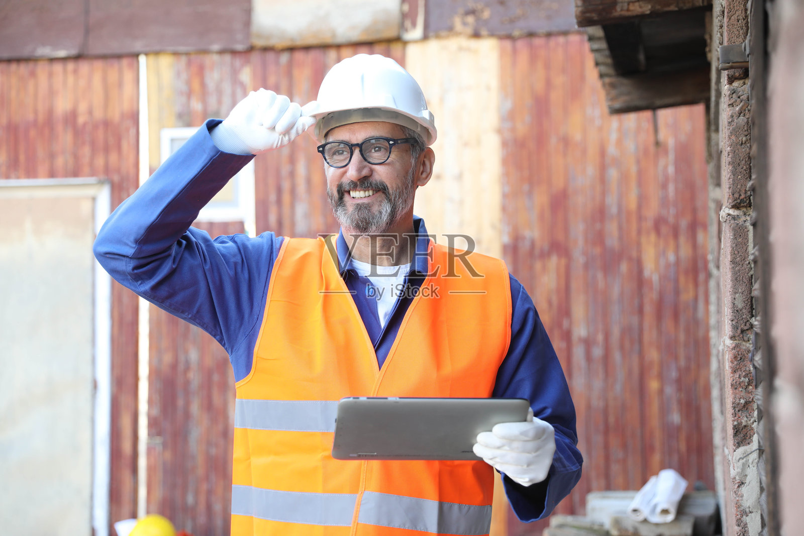 一位年长的男性白人建筑师、建筑承包商或工程师，在建筑工地上使用数字平板电脑的肖像照片摄影图片