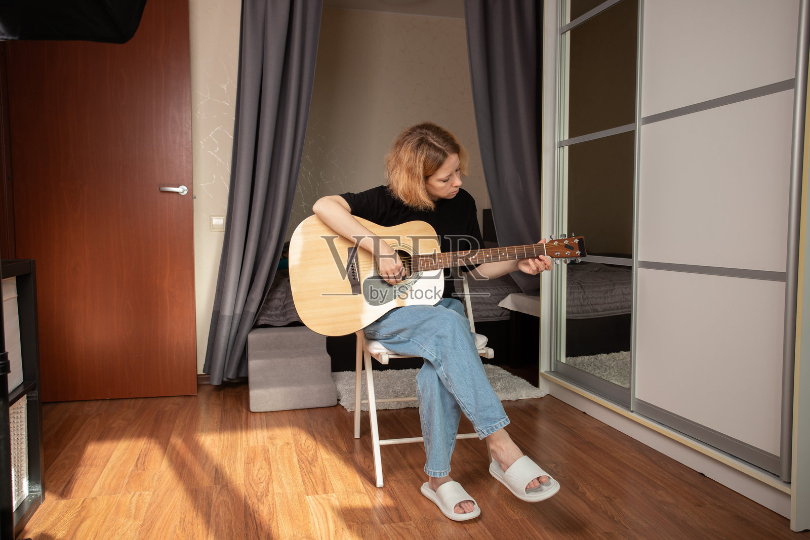 女人在舒适的室内环境中弹吉他，享受轻松的生活方式，探索她的音乐教育。照片摄影图片
