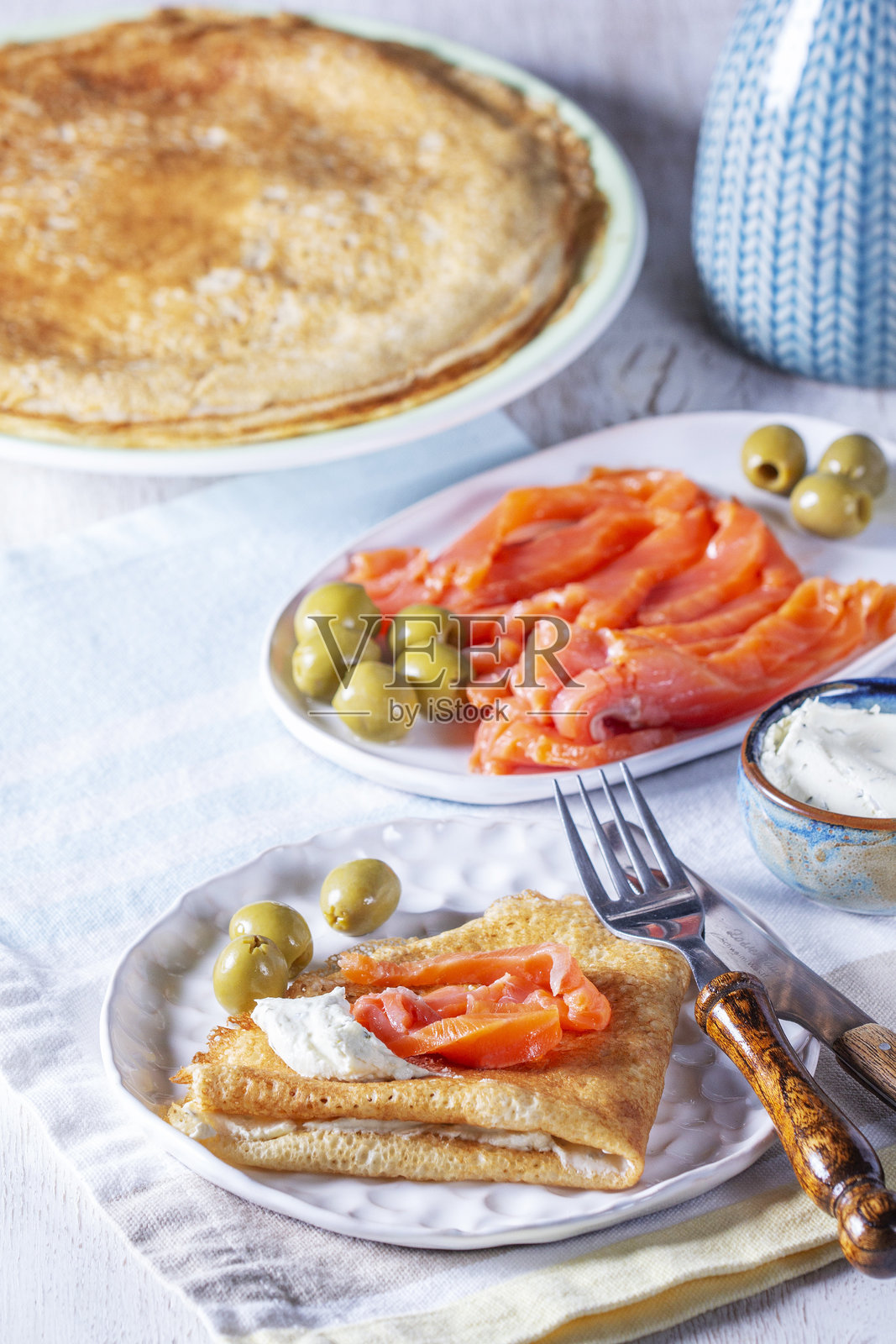 配有腌三文鱼、奶酪和橄榄的煎饼。传统的马斯连尼察或狂欢节菜肴。照片摄影图片