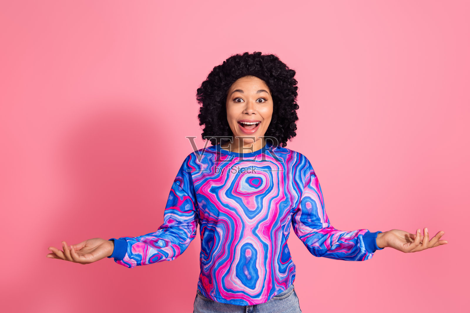 穿着时尚衣服的快乐积极女性在粉色背景上手持空白空间新闻照片摄影图片