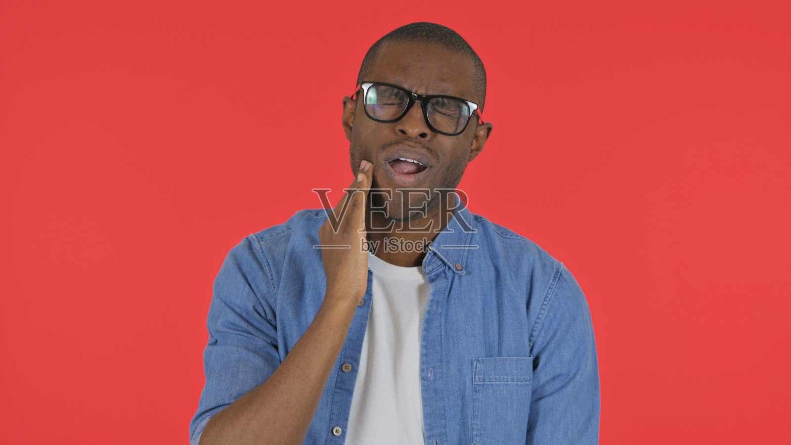 红色背景下的非洲男子因牙痛而显得随意，肖像照照片摄影图片