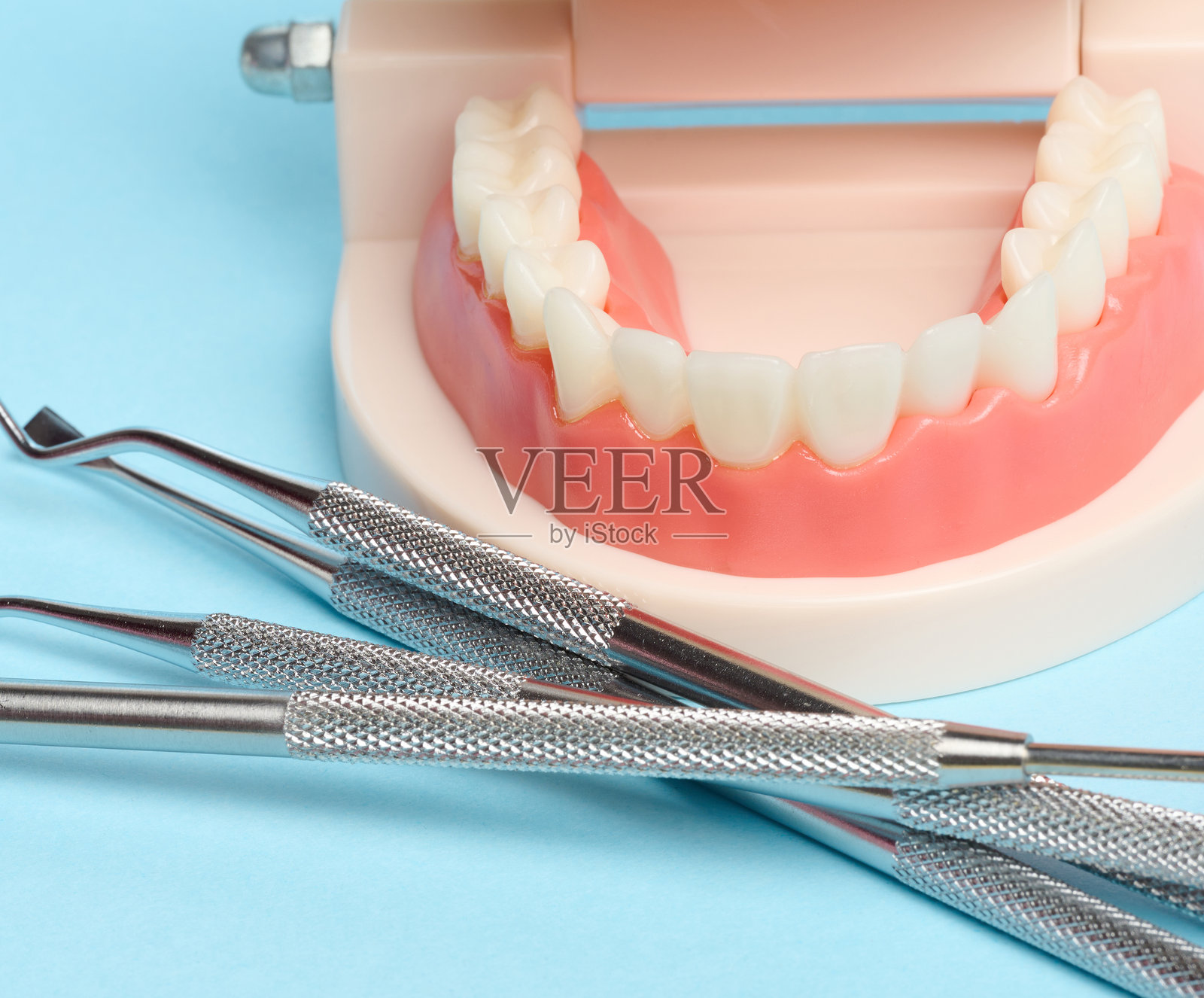 蓝色背景上的人类下颌塑料模型和医疗器械照片摄影图片