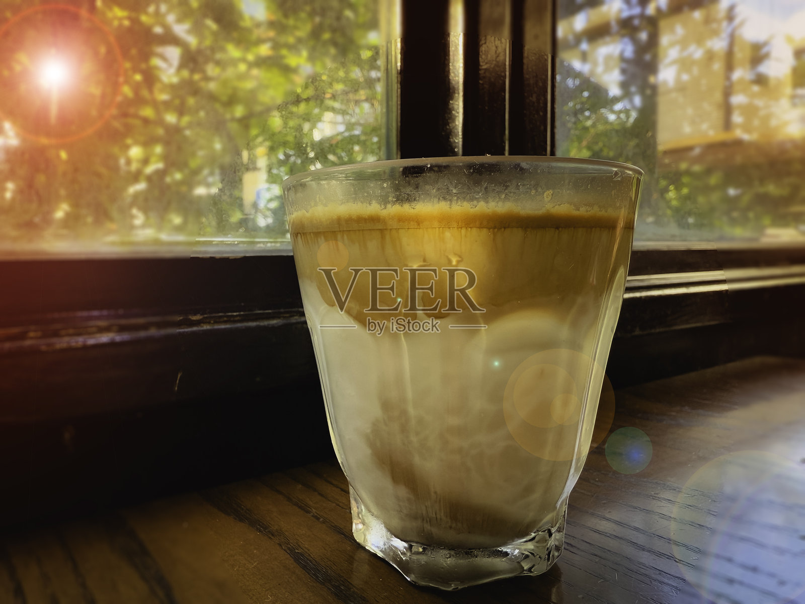 窗边的牛奶咖啡，阳光在玻璃上反射。照片摄影图片