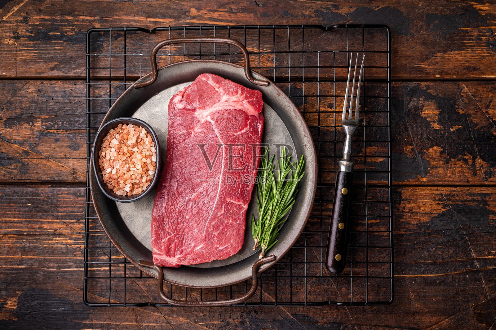 准备烹饪的生牛臀肉牛排，配有香草。木质背景。俯视图。照片摄影图片