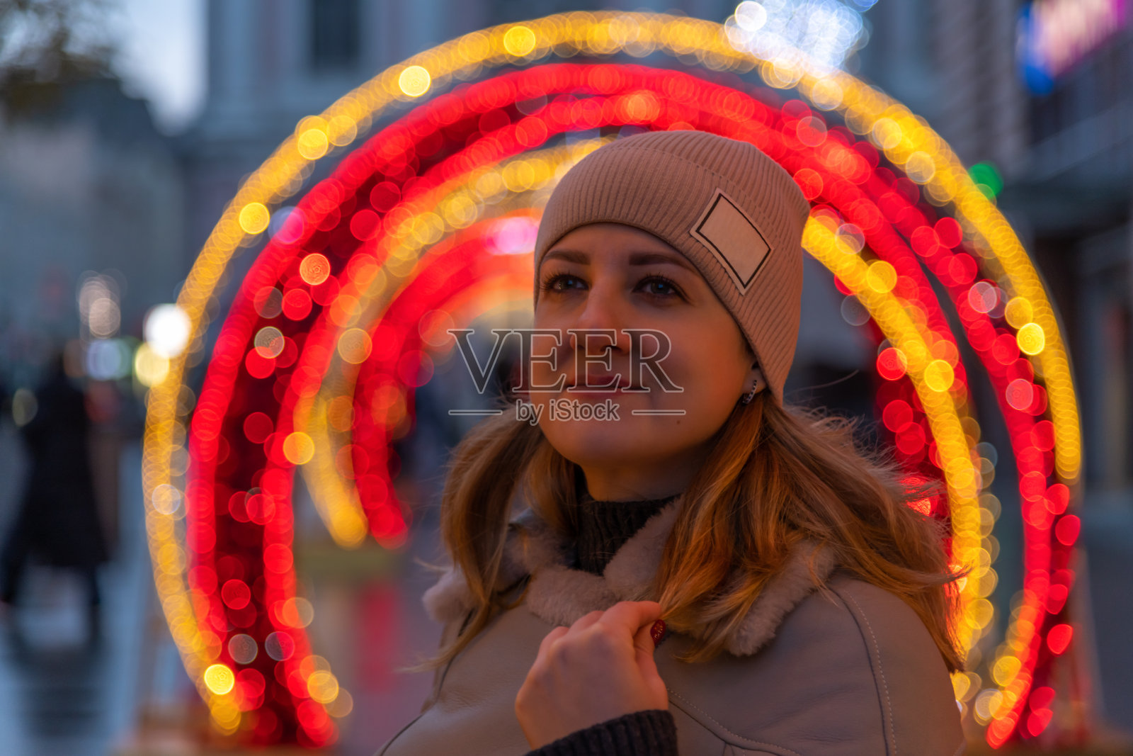 女人站在拱形的灯光装饰旁边照片摄影图片