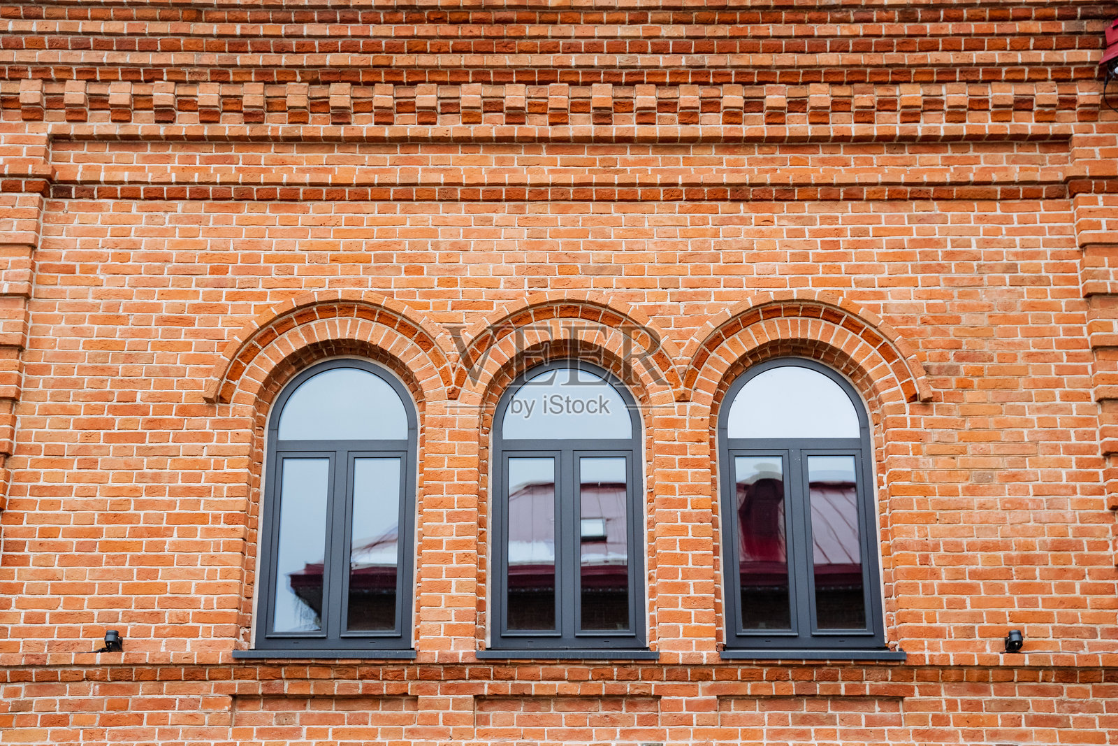 这是一座砖砌建筑，侧面显著展示着三个优雅的拱形窗户，为其整体美感增添了魅力和个性。照片摄影图片