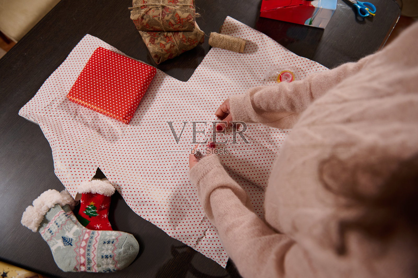 一个人在桌子上用节日袜子和波点纸包裹礼物照片摄影图片