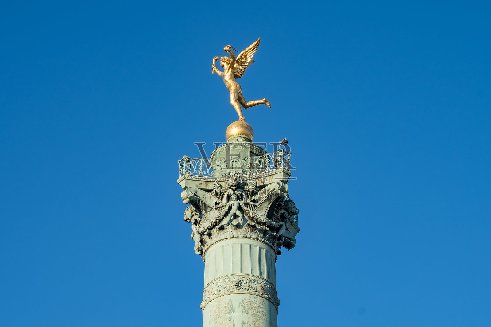 巍峨的金色天使矗立在高耸的柱子上,映衬着湛蓝的天空照片摄影图片