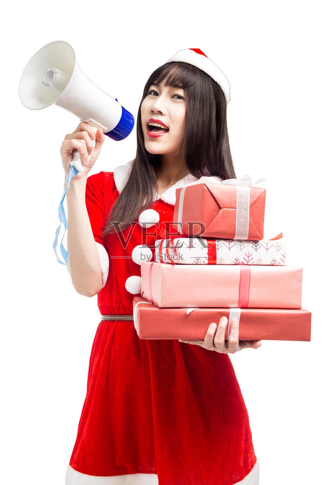 穿着圣诞老人服装的亚洲女性手持扩音器和一堆礼物照片摄影图片