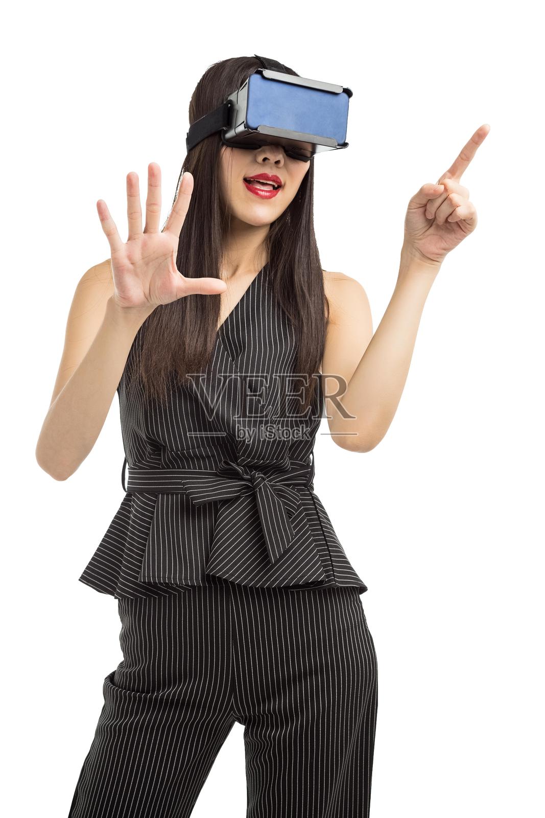 戴着虚拟现实头盔并指向的亚洲女性照片摄影图片