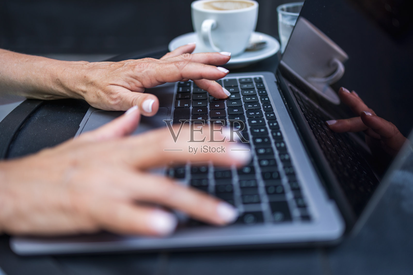 手部特写在笔记本电脑上打字，背景有一杯咖啡照片摄影图片