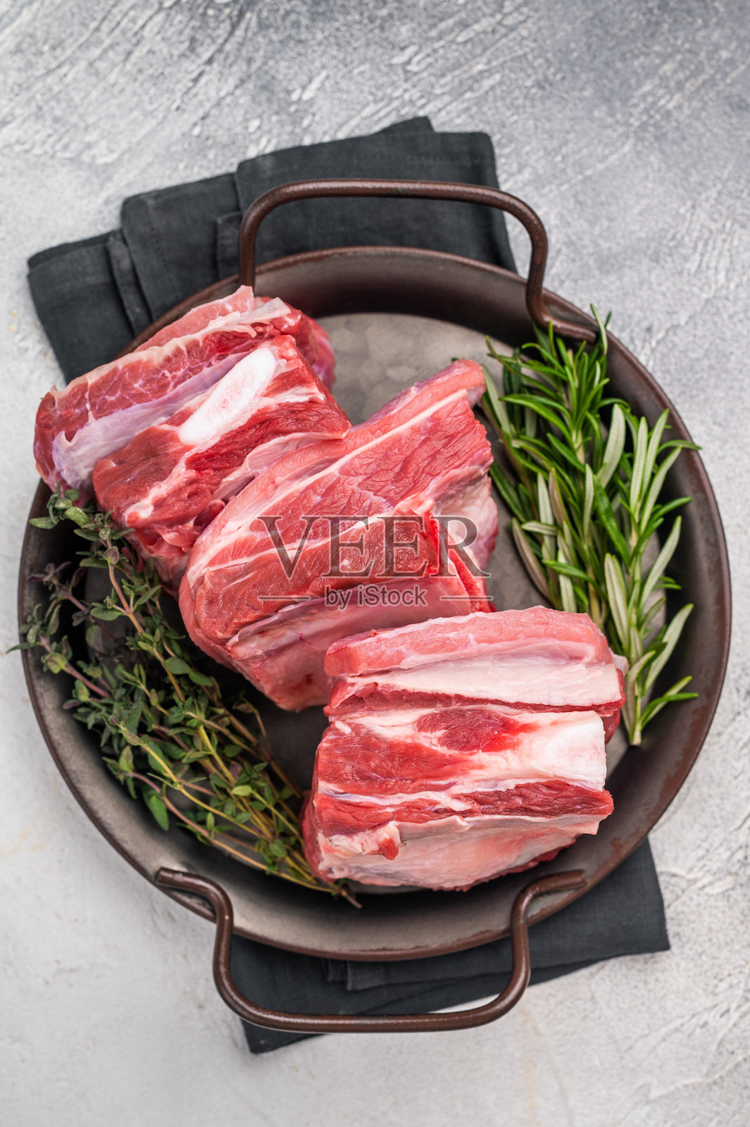 生羊肋排，带肋骨的新鲜羊肉。灰色背景。俯视图。照片摄影图片