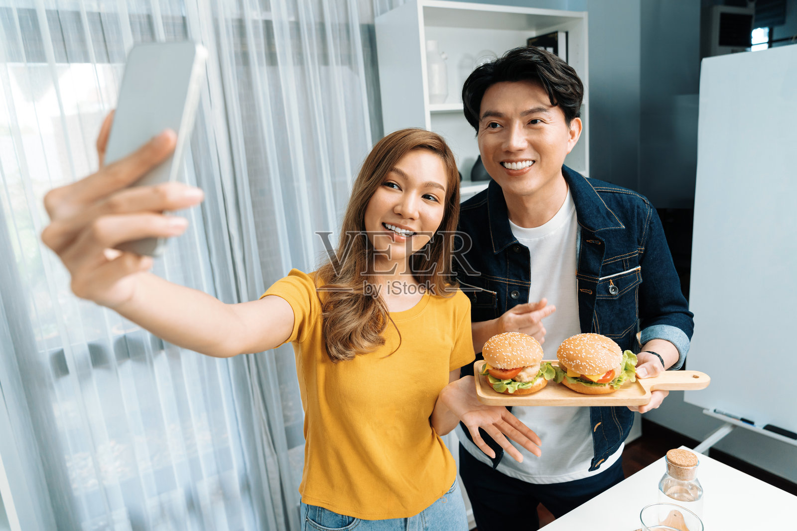 厨师网红用智能手机拍照，手里拿着双层汉堡。照片摄影图片