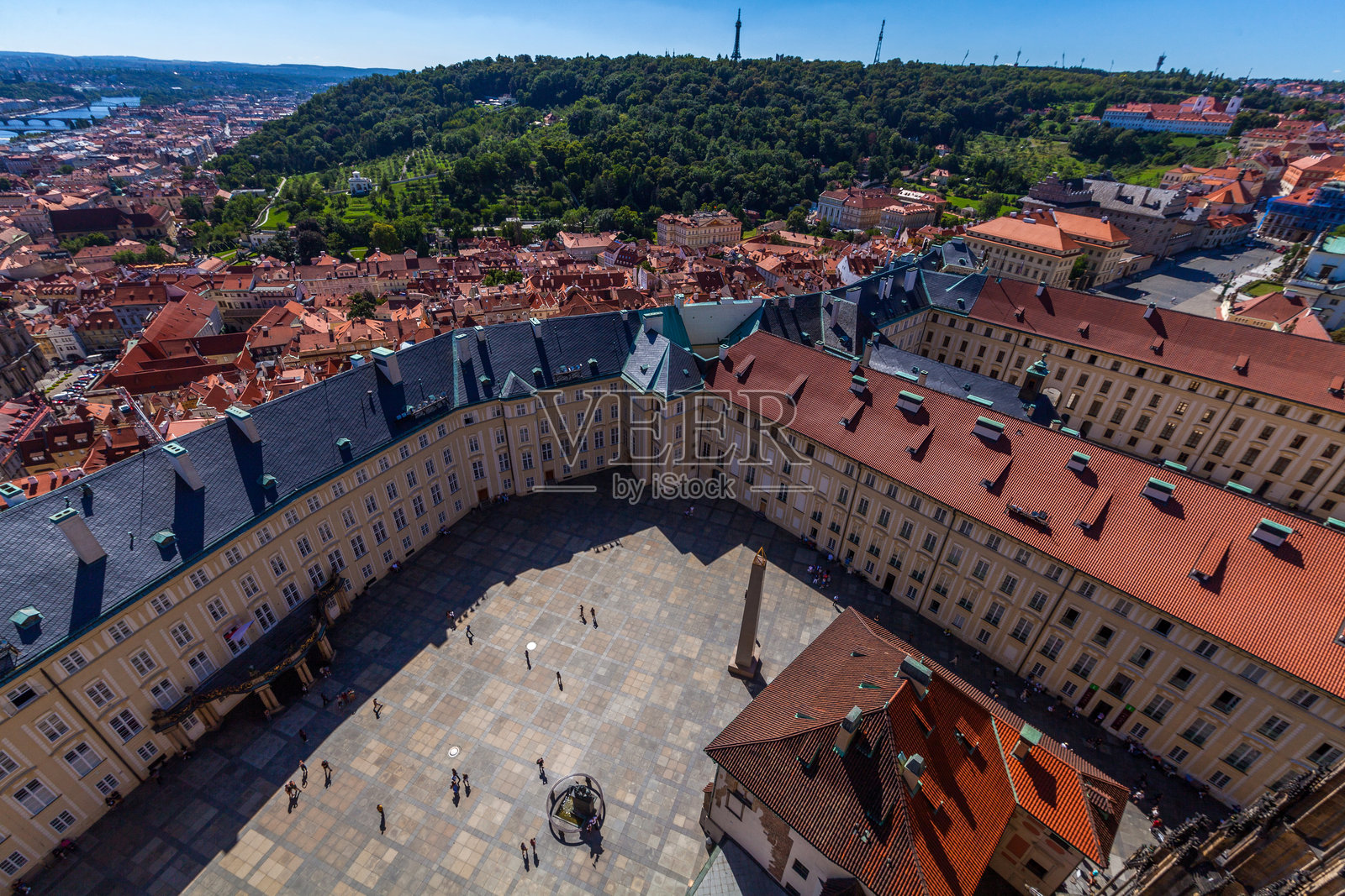 高角度城市景观，展现了一个广阔的欧洲城市，红色瓦顶的房屋，前景有石制栏杆，背景是晴朗的蓝天。照片摄影图片