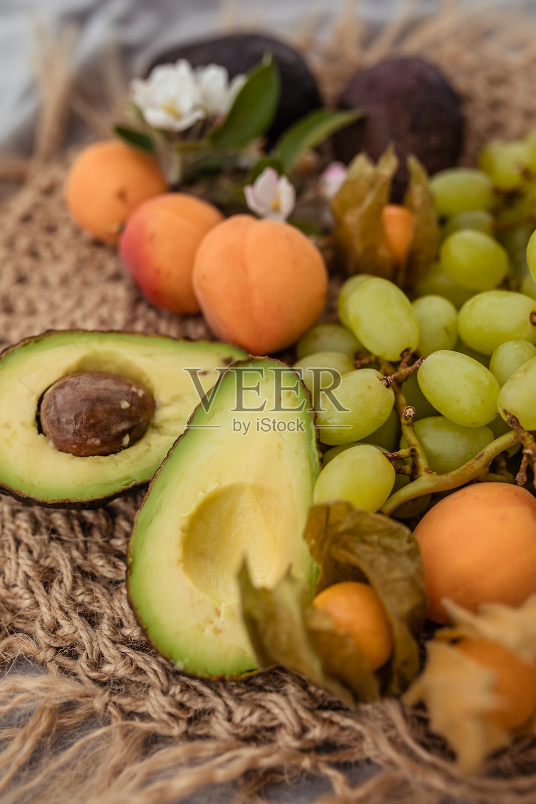 自然中的夏季野餐，草编盘子里放着鳄梨、桃子和葡萄照片摄影图片